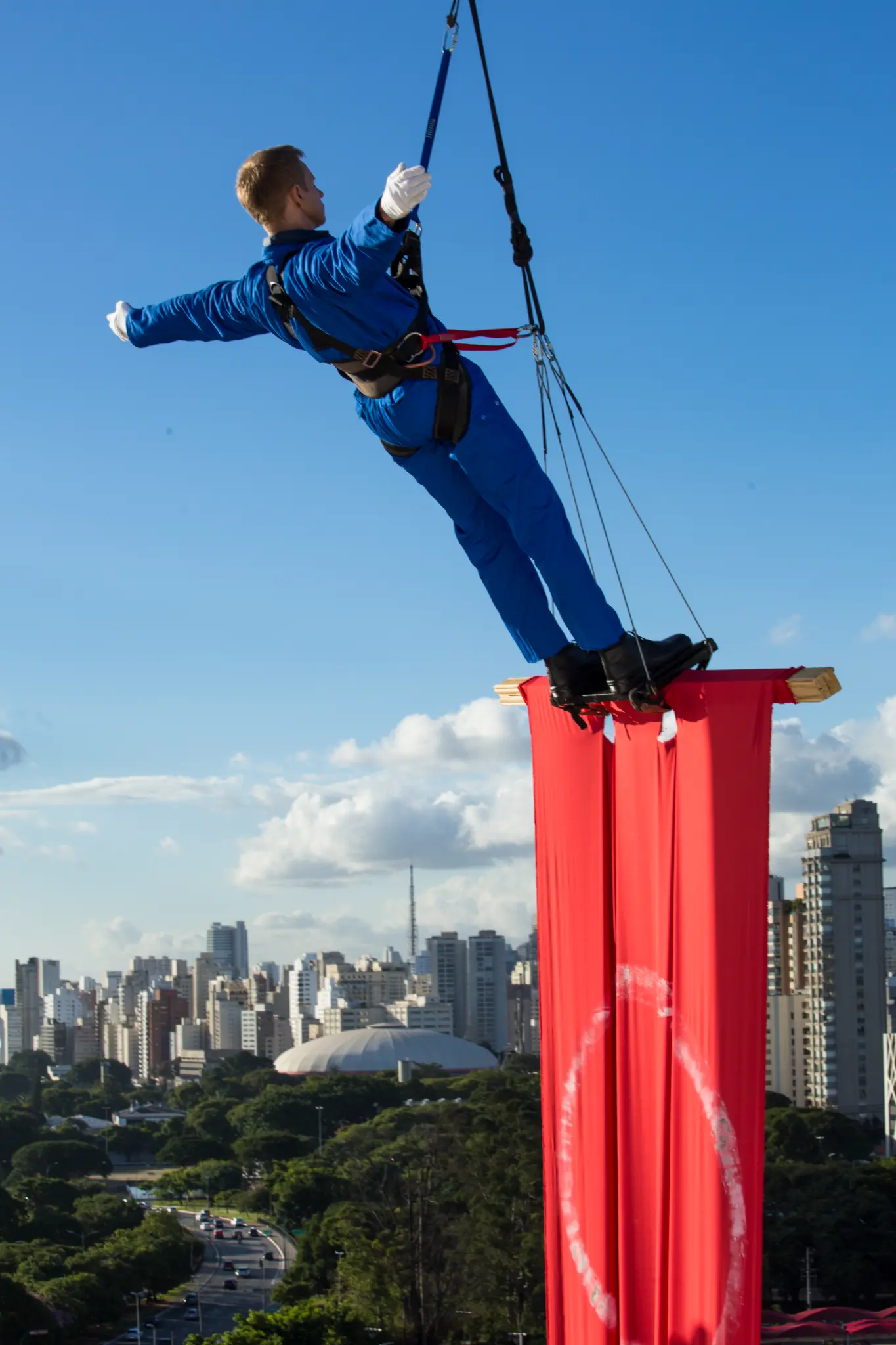 Fyodor Pavlov-Andreevich suspended above São Paulo on a red fabric structure