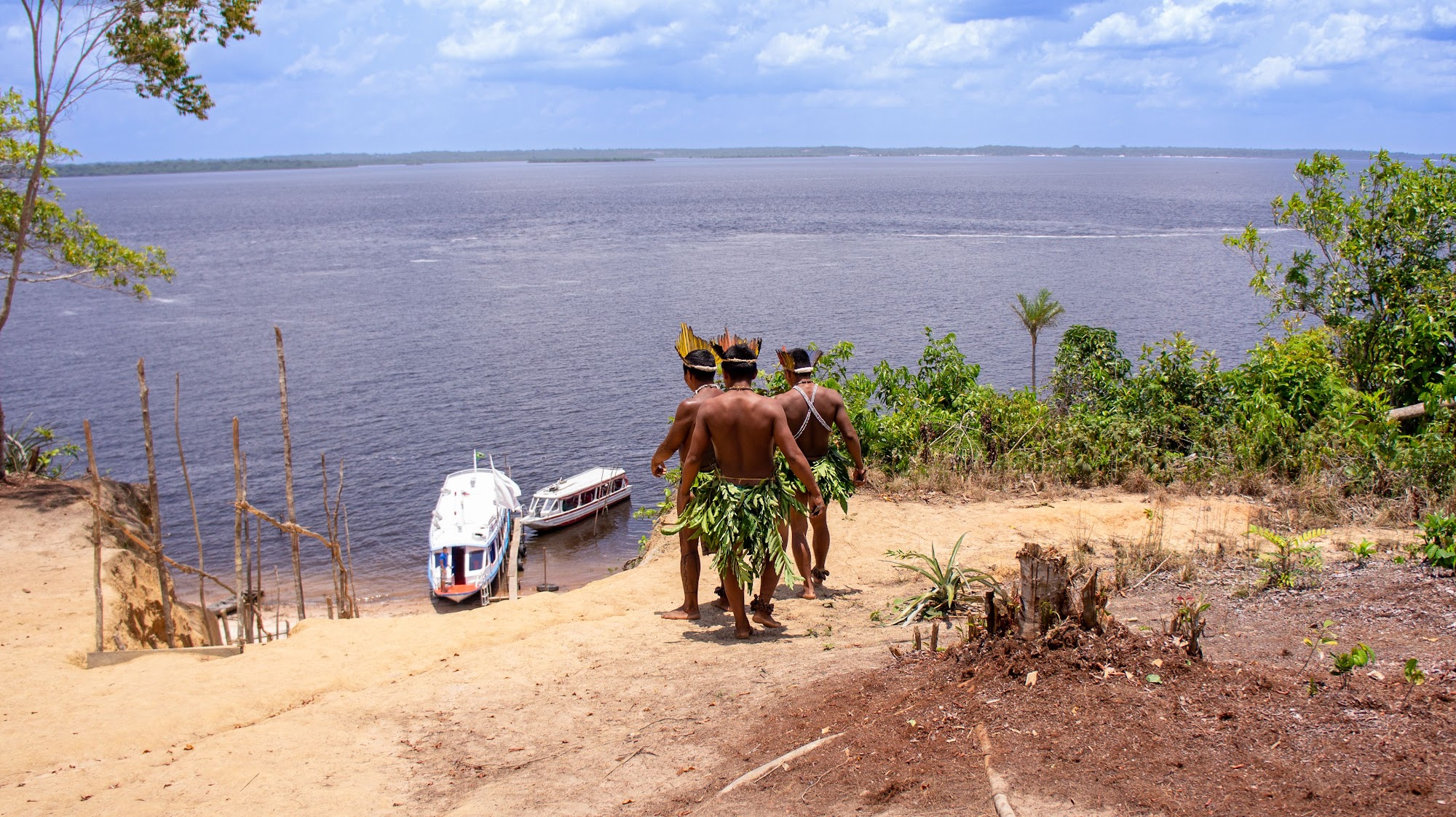 Pirarucu community members walking towards boats on an Amazon riverbank
